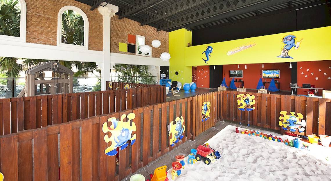 Innenansicht des Kinderbereichs im IFA Villas Bavaro Hotel mit Sandkasten, Spielzeug und bunten Wänden.