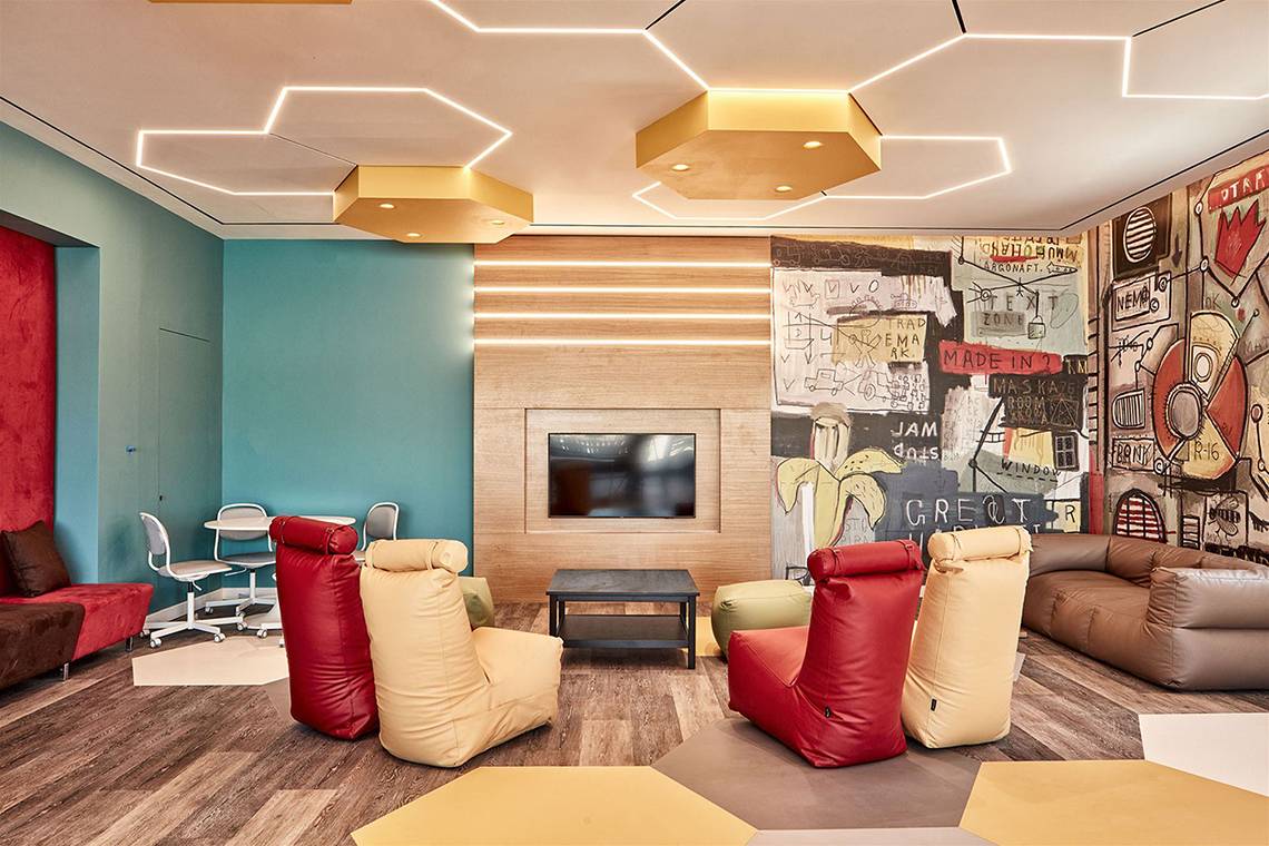 Lounge-Bereich im Atlantica Dreams Resort mit bunten Sitzsäcken, Tisch, Fernseher und Wandmalerei.