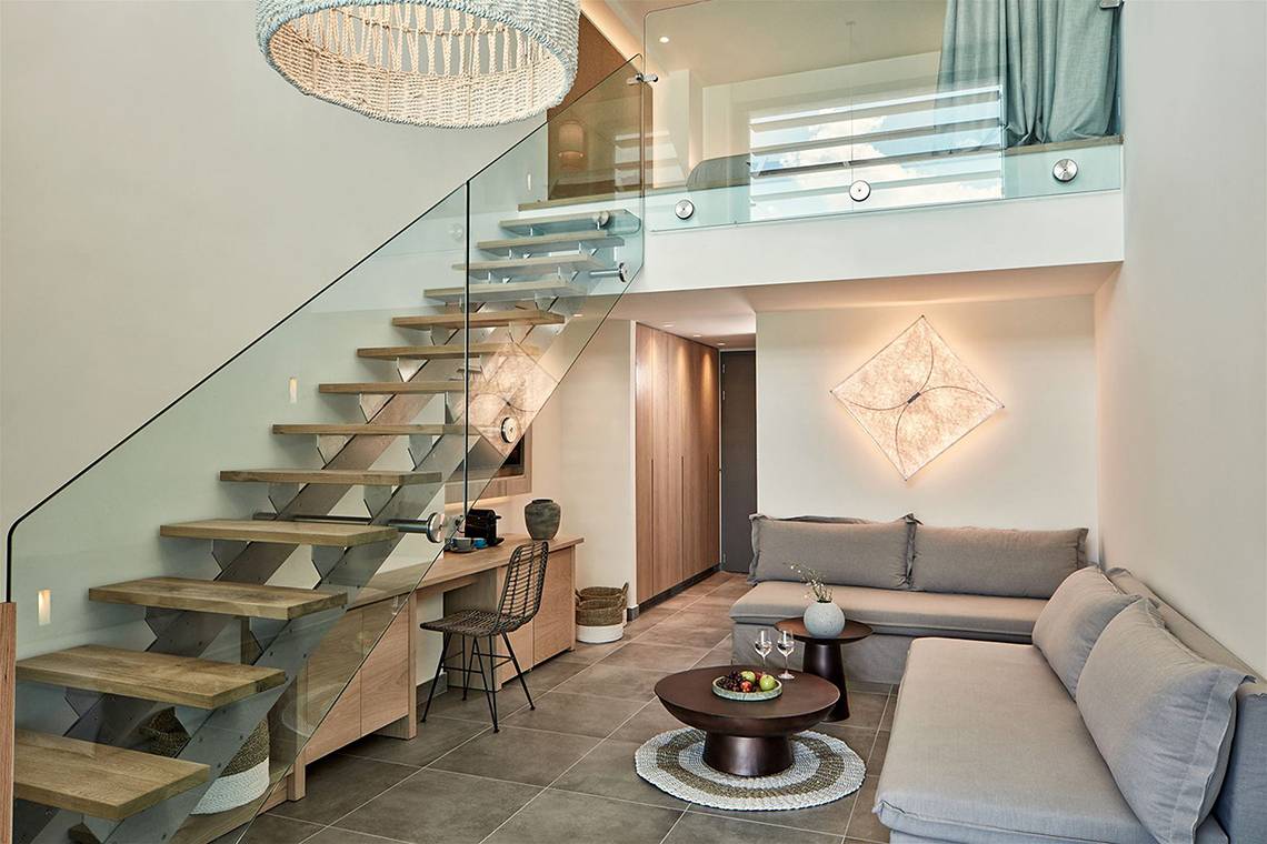 Innenraum des Atlantica Dreams Resorts mit Couch, Tisch, Treppe und Glasbalkon.