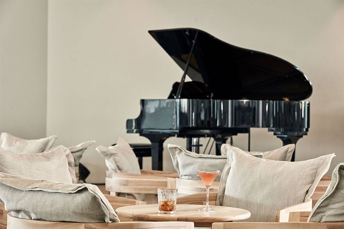 Loungebereich im Atlantica Dreams Resort mit schwarzem Klavier und Getränken auf dem Tisch.