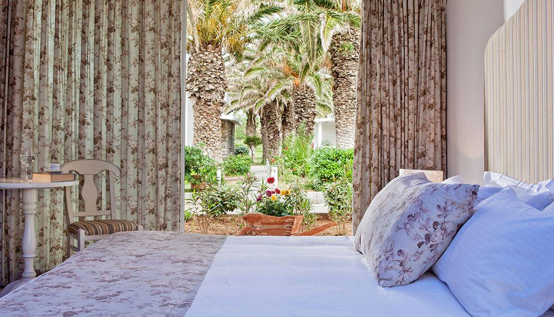 Hotelzimmer im Civitel Creta Beach mit Blick auf einen Garten und Palmen.