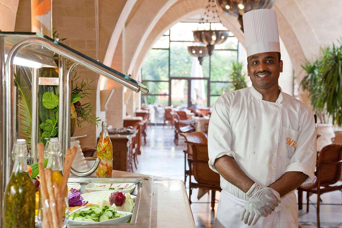 Koch im Restaurant des Grand Waterworld Makadi Hotels, das Essensbuffet im Hintergrund