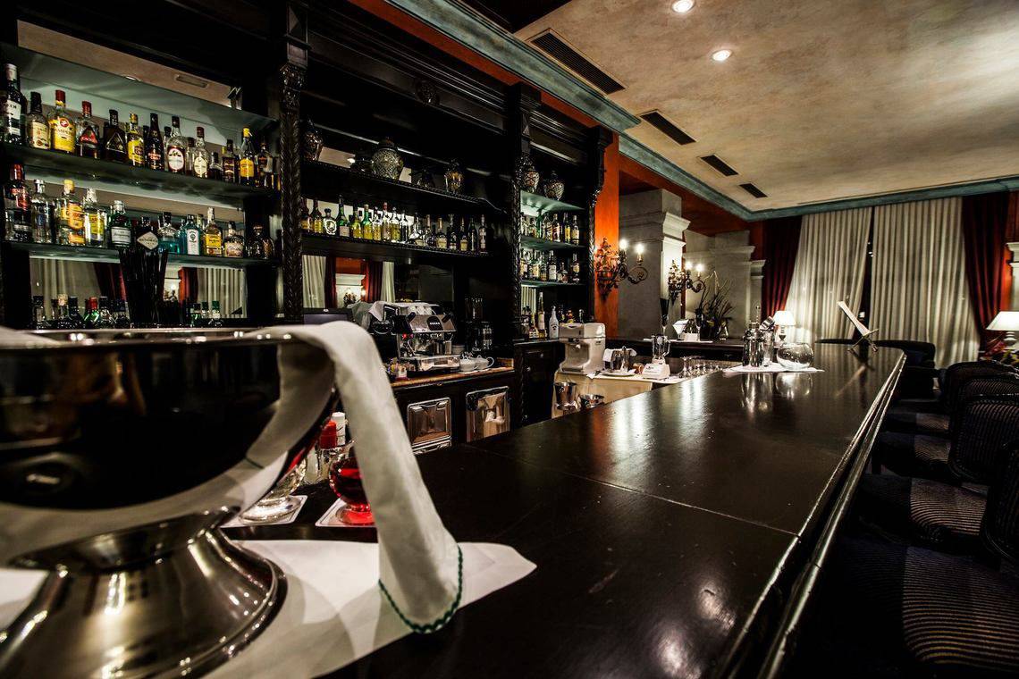 Innenansicht der Bar im Europe Villa Cortes Hotel mit einer langen Bartheke und vielen alkoholischen Getränken.