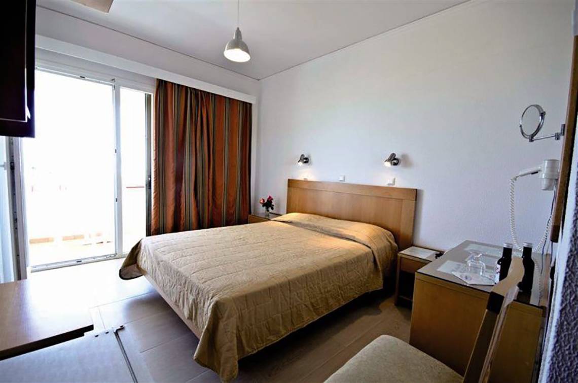 Ein ruhiges Hotelzimmer im Tropical Sol mit einem Bett, einem Tisch und einem Fenster mit Blick nach draußen.