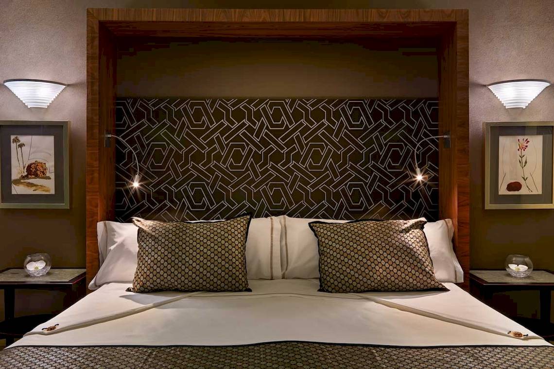 Jardines de Nivaria Hotelbett mit gemusterter Wand und zwei Nachttischen.