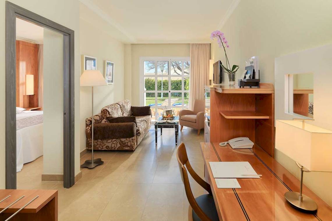 Innenansicht eines Hotelzimmers im Jardines de Nivaria mit Wohnzimmermöbeln und Schreibtisch.
