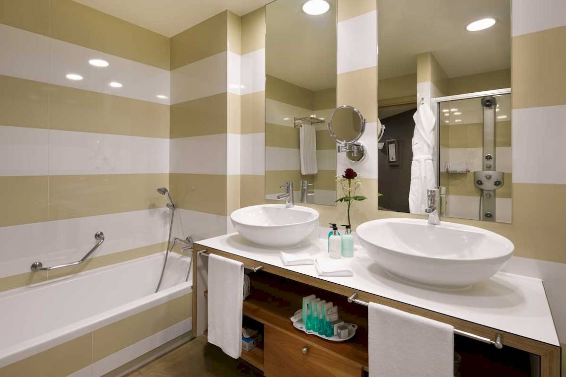Badezimmer im Jardines de Nivaria Hotel mit zwei Waschbecken, Badewanne und Dusche.