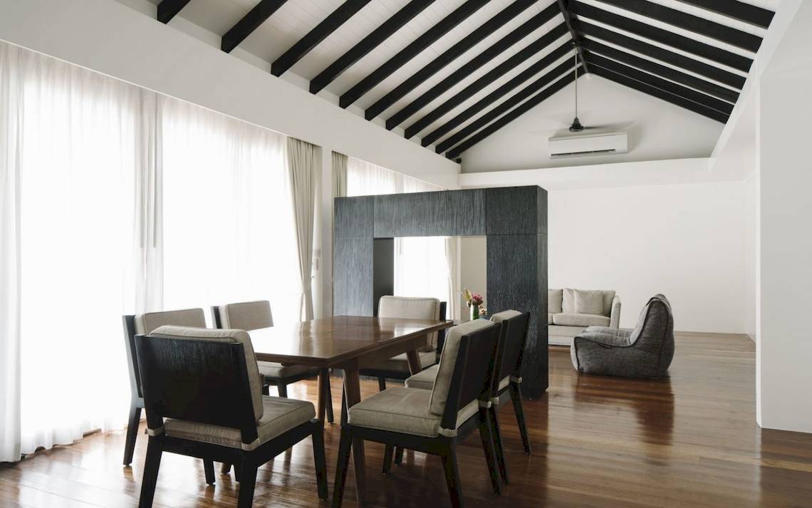 Innenansicht des Speisezimmers im Noku Maldives Hotel mit Holzboden, weißen Wänden und Möbeln.