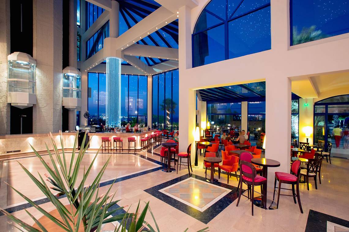 Innenansicht der Lobby des Kresten Palace Hotels mit großen Fenstern und moderner Einrichtung.