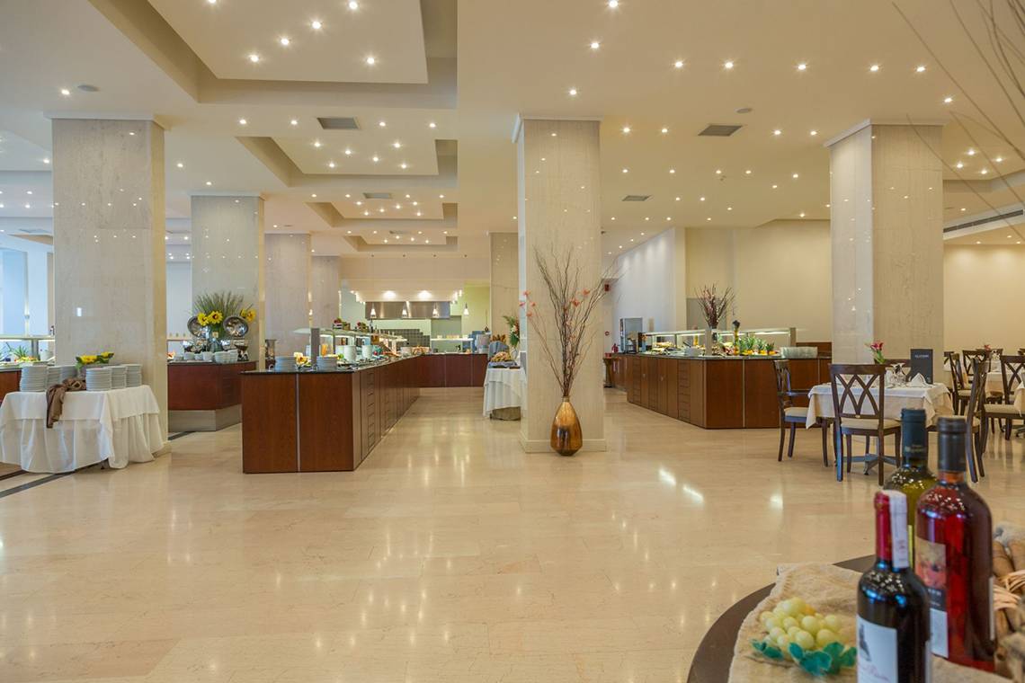Frühstücksbuffet im Kresten Palace Hotel mit Tisch und Stühlen, gedeckten Tischen und Getränken.