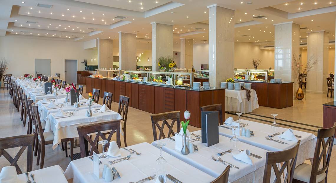 Restaurant im Kresten Palace Hotel mit langen Tischen, Stühlen und einer langen Buffettheke.