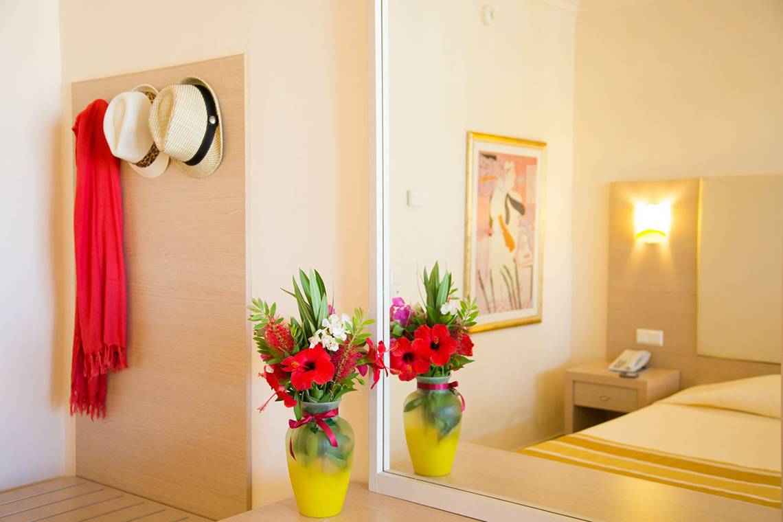 Ein Hotelzimmer mit zwei gelben Vasen voller Blumen, reflektiert in einem Spiegel, Kresten Palace Hotel.