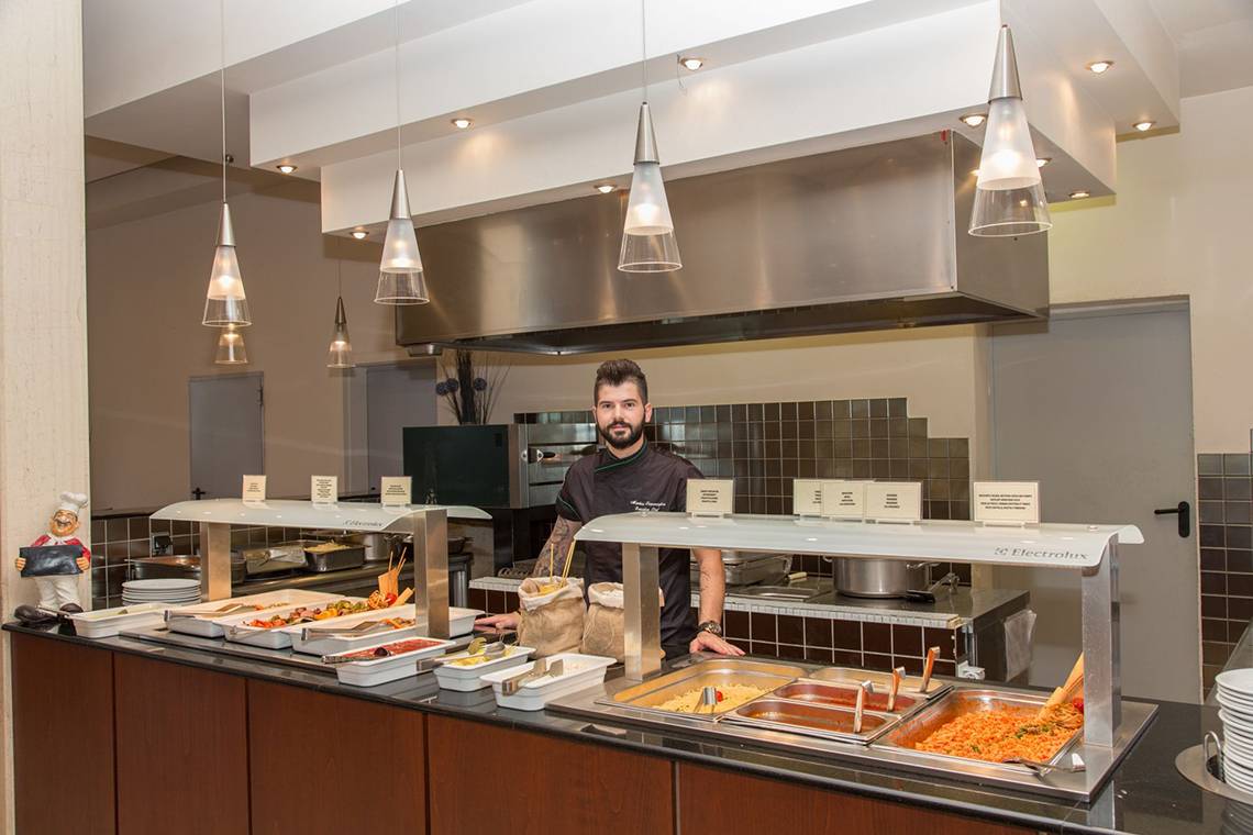 Buffet-Tisch im Kresten Palace Hotel mit verschiedenen Speisen und einem Koch im Hintergrund.