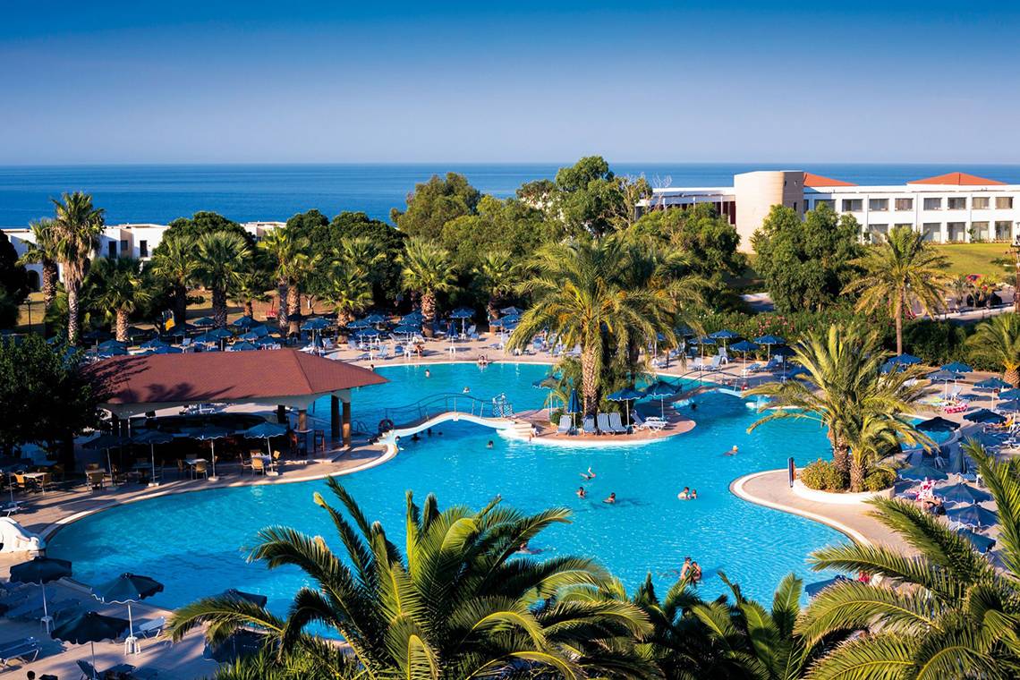 Außenbereich des Kresten Palace Hotels mit Swimmingpool und Palmen.