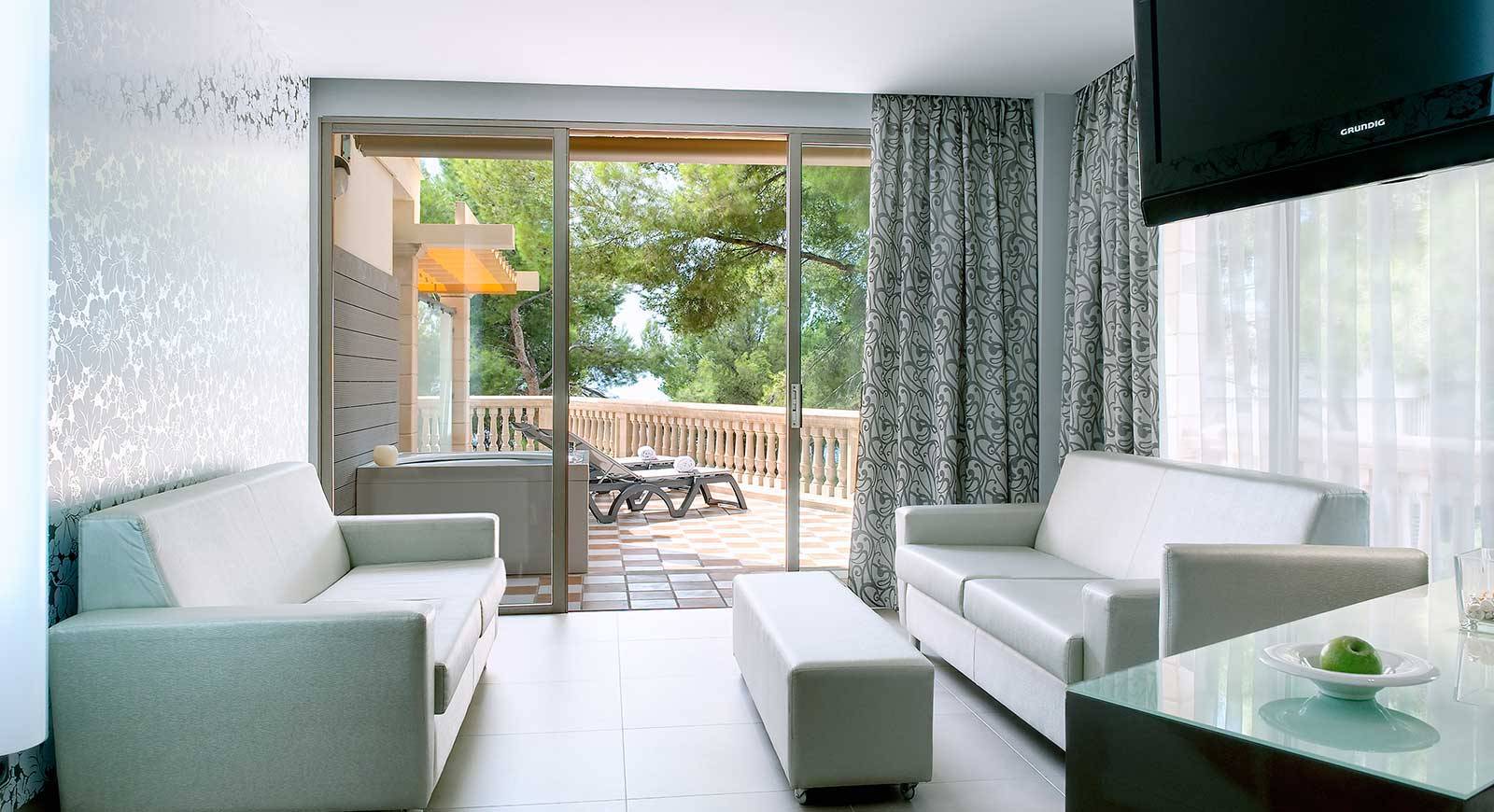 Wohnzimmer mit Balkon im Barcelo Illetas Albatros Hotel, mit modernem Interieur und Blick auf den Garten.