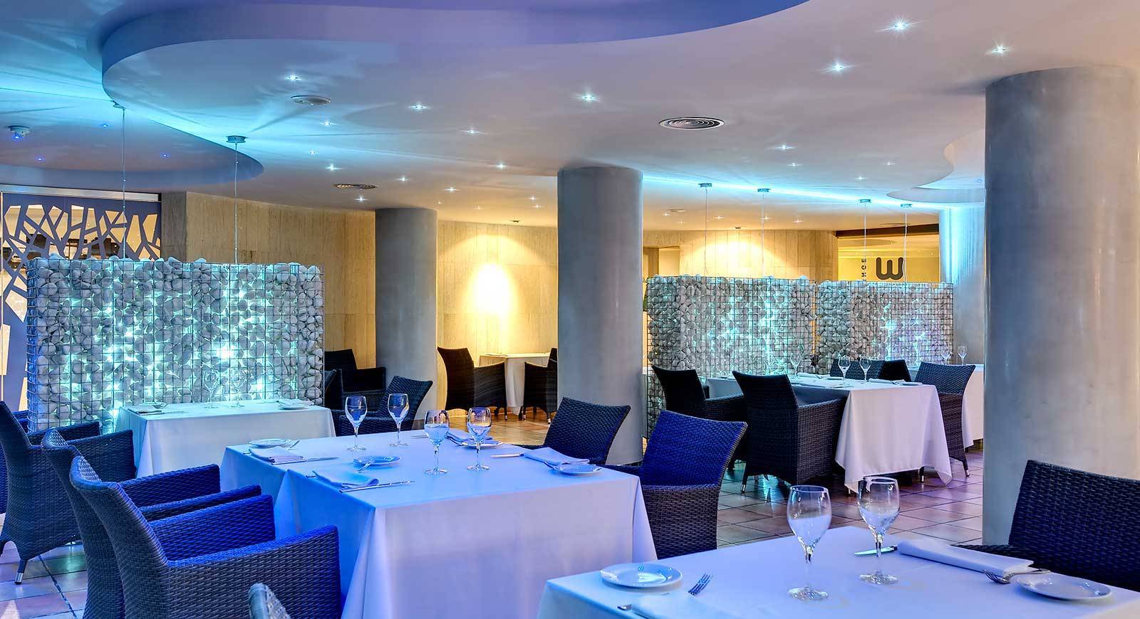Innenansicht des Restaurants im Barcelo Illetas Albatros Hotel mit blauen Möbeln und weißen Tischen.