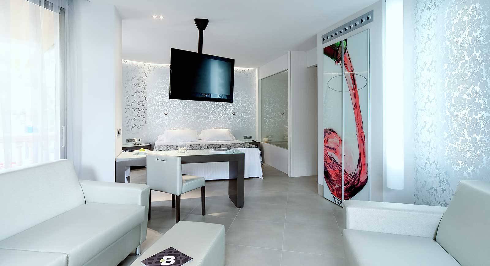 Innenraum des Barcelo Illetas Albatros Hotel mit weißem Bett, Schreibtisch und Fernseher.