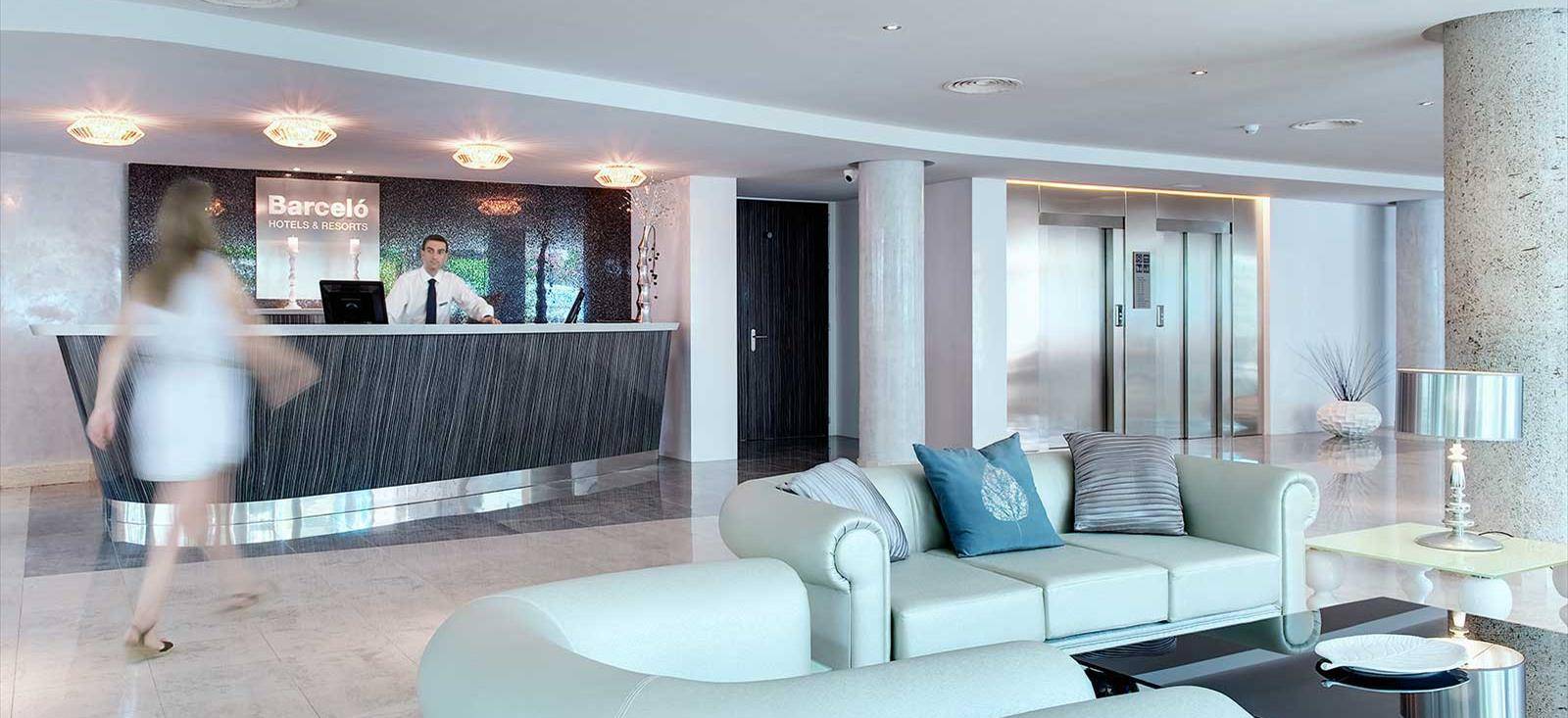 Empfangsbereich des Barcelo Illetas Albatros Hotel mit Rezeption, Sofas und Lampen.
