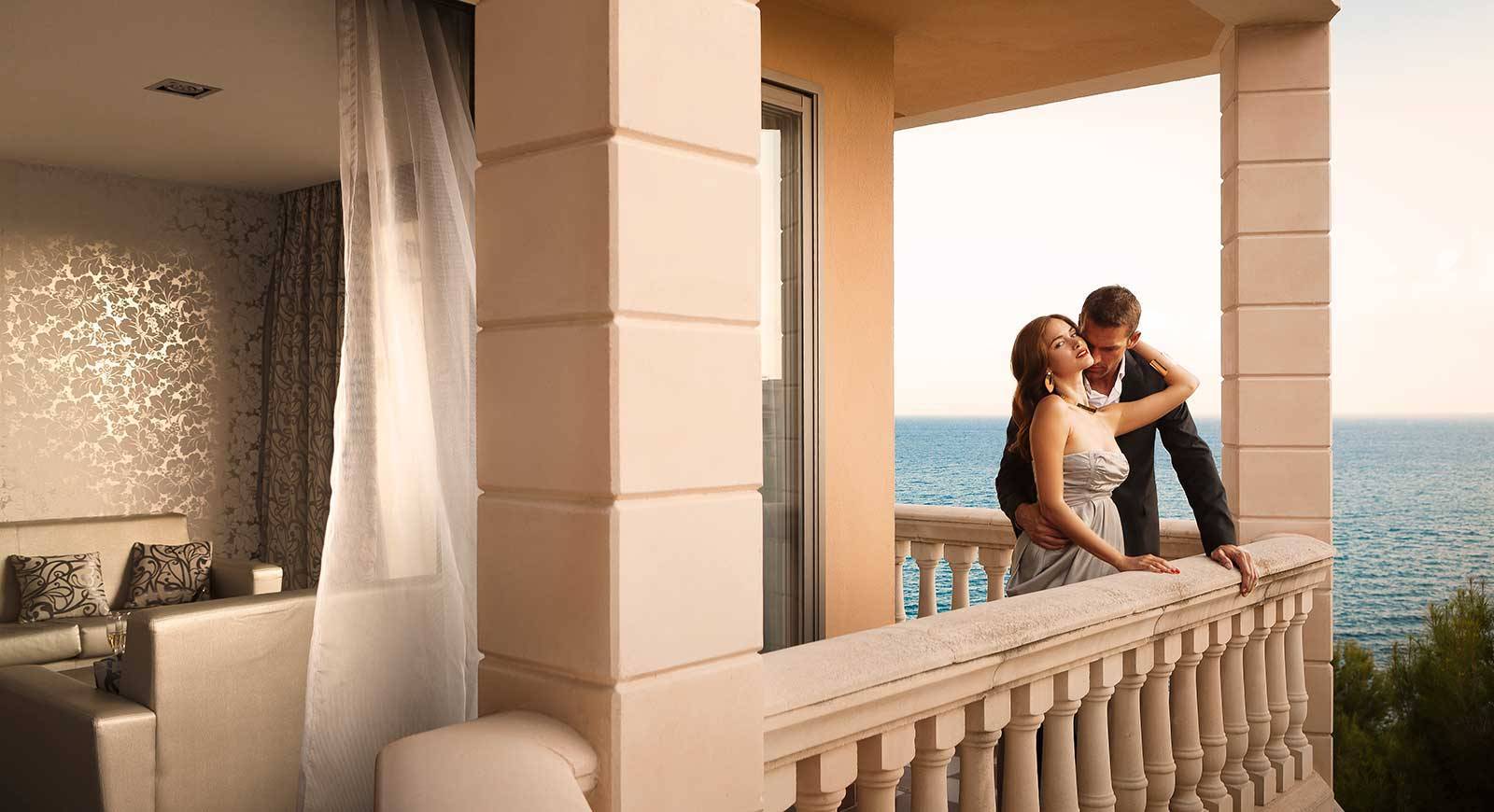 Ein Paar steht sich küssend auf dem Balkon des Barcelo Illetas Albatros Hotels.