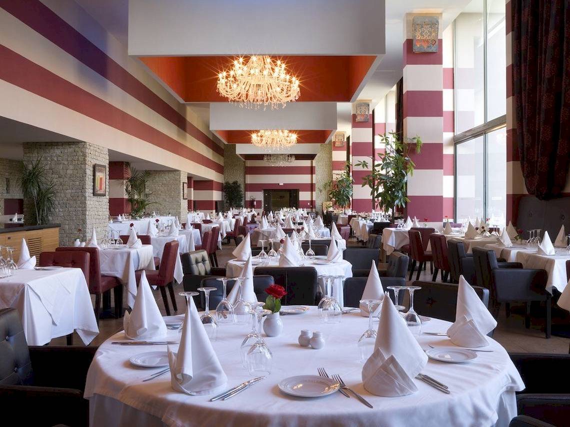 Das elegante Restaurant des Royal Atlas & Spa Hotels mit gemusterten Wänden und Tischdekoration.