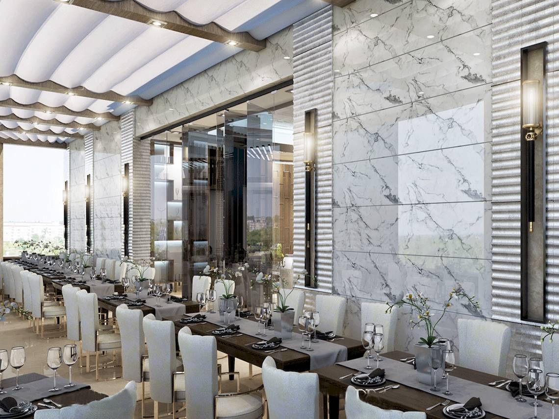 Innenansicht des Restaurants im Belad Bont Resort mit Marmorwänden und langen Tischen.
