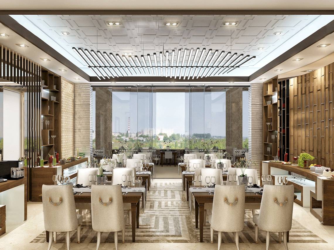 Innenansicht des Restaurants im Belad Bont Resort mit runden Tischen, Stühlen und großen Glaswänden.