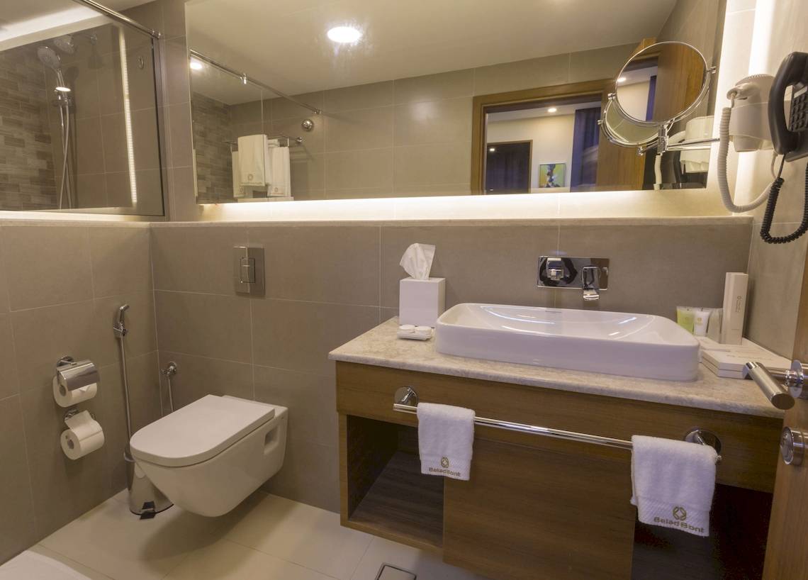 Badezimmer des Belad Bont Resorts mit moderner Ausstattung, einschließlich einer Toilette, eines Waschbeckens und eines Spiegels.