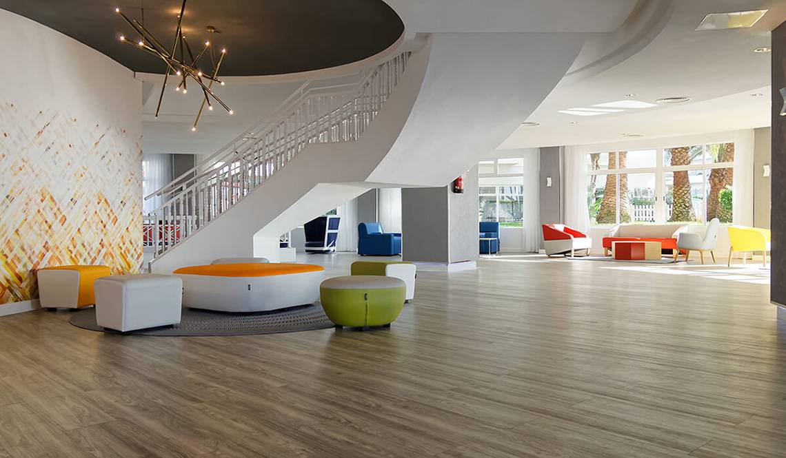 Servatur Waikiki Hotel Lobby mit weißen Treppen, bunten Stühlen und einem runden Tisch.