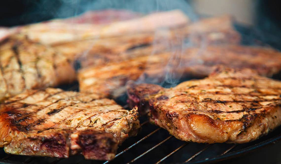 Gegrilltes Fleisch auf einem Grillrost mit Rauch und Feuer