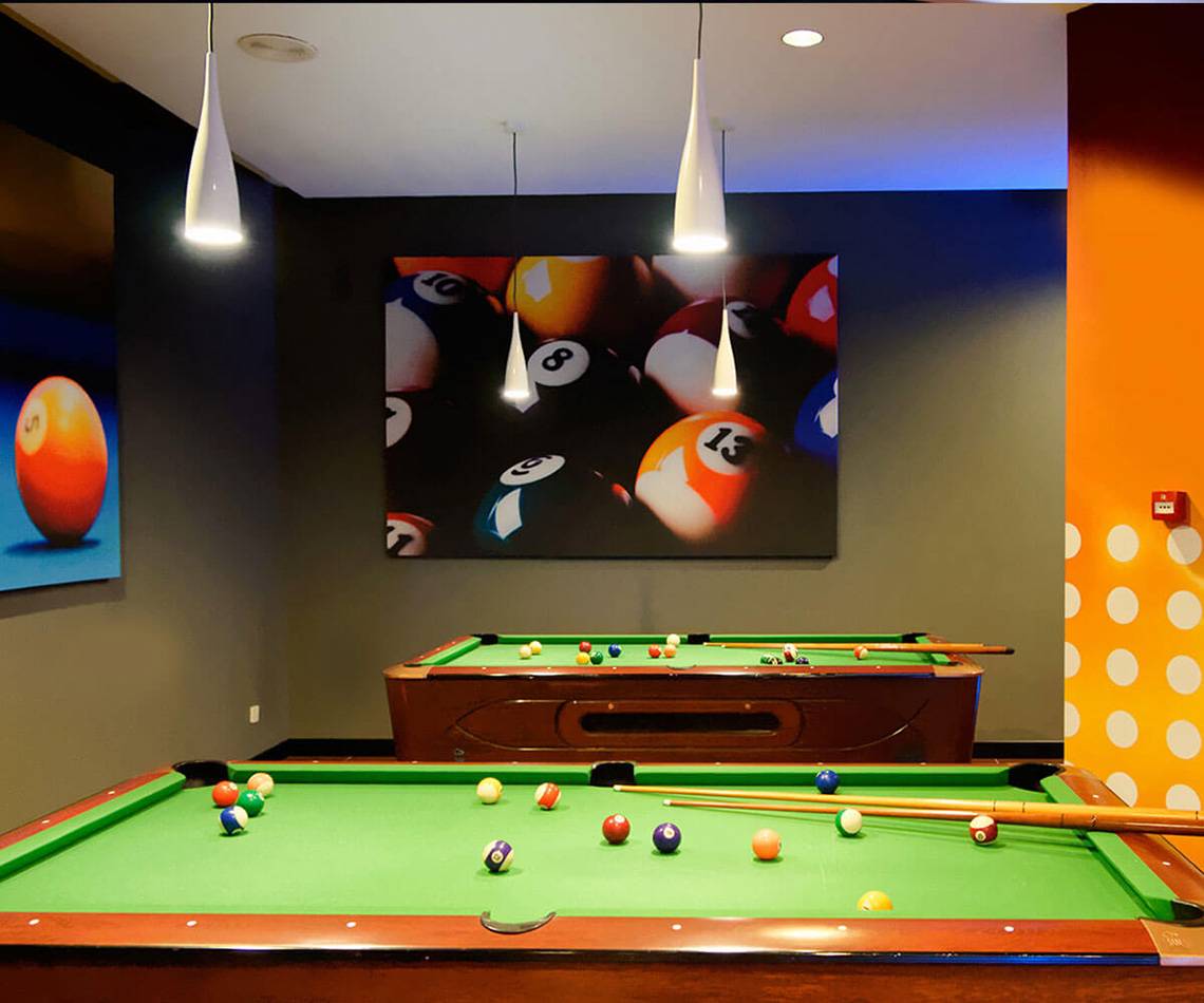 Billardraum im Servatur Waikiki Hotel mit zwei Billardtischen, einer an der Wand und vielen bunten Bällen.