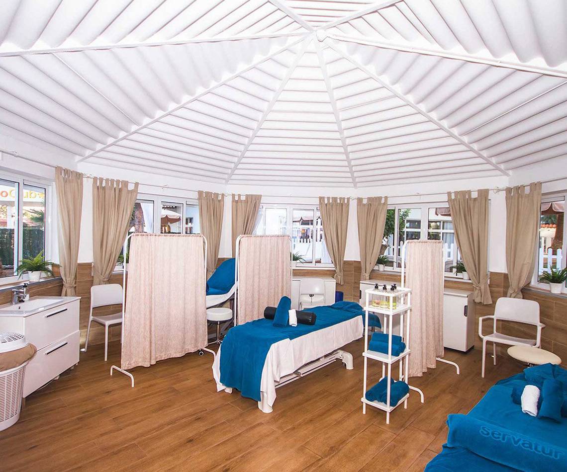 Behandlungsraum im Servatur Waikiki Hotel mit Massageliegen und blauen Laken.
