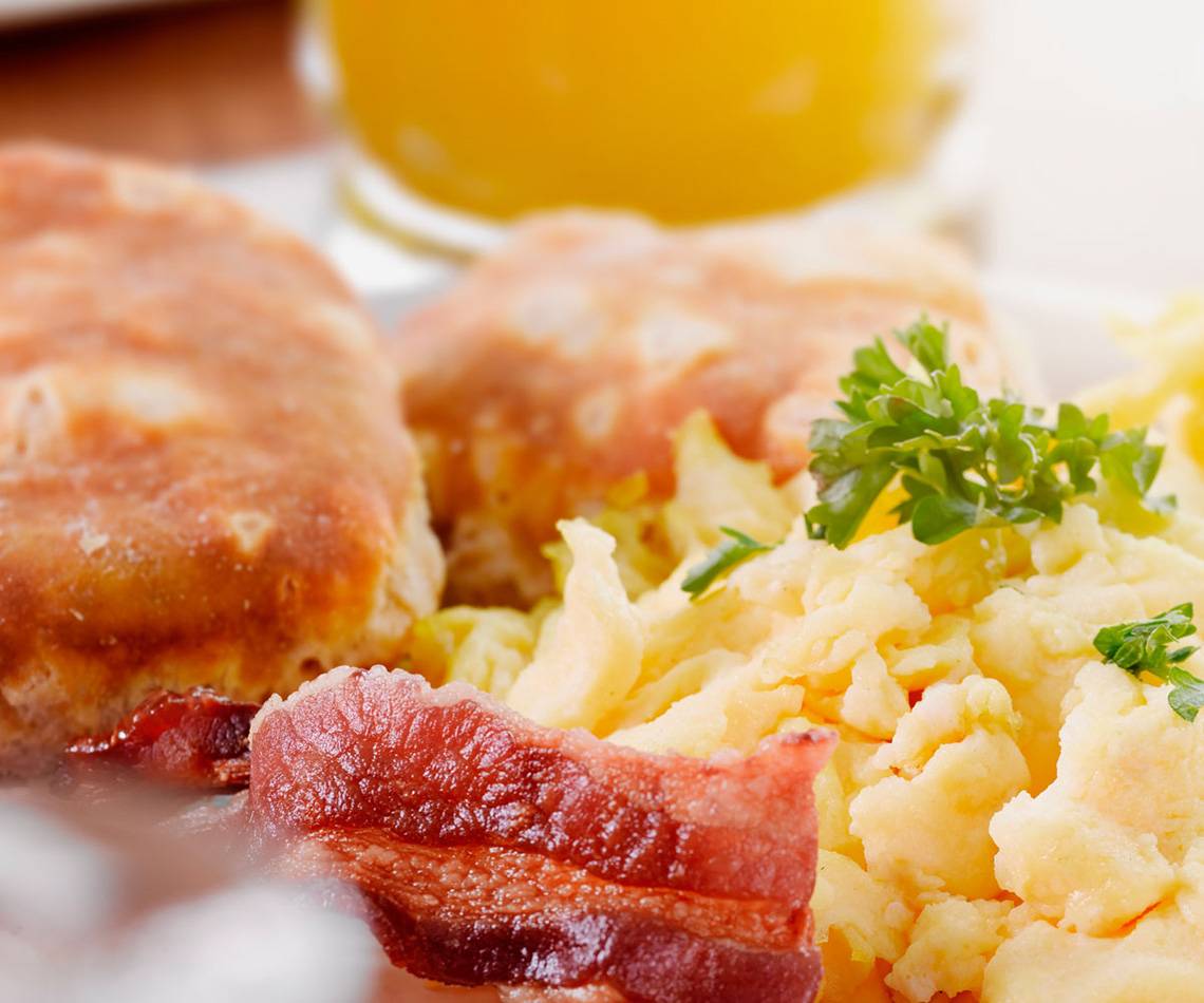 Frühstück mit Speck und Eiern, serviert auf einem weißen Teller.