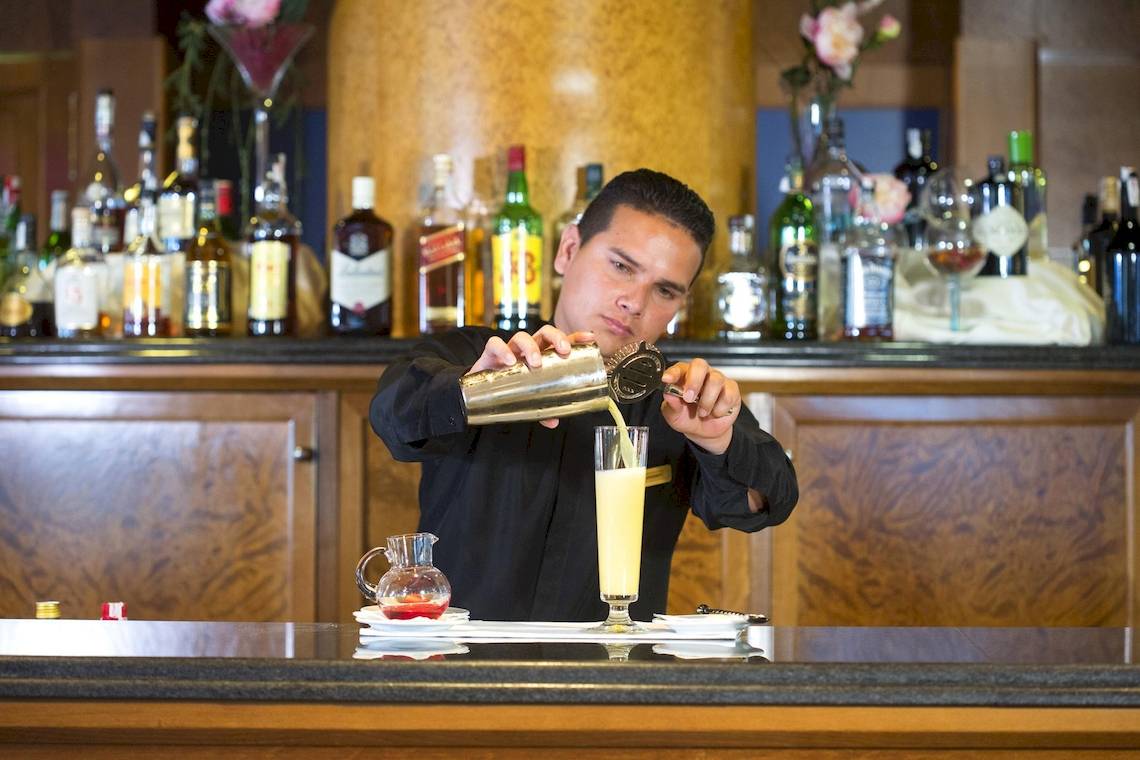 Ein Barkeeper mischt einen Cocktail im Hipotels Hipocampo Playa Hotel.