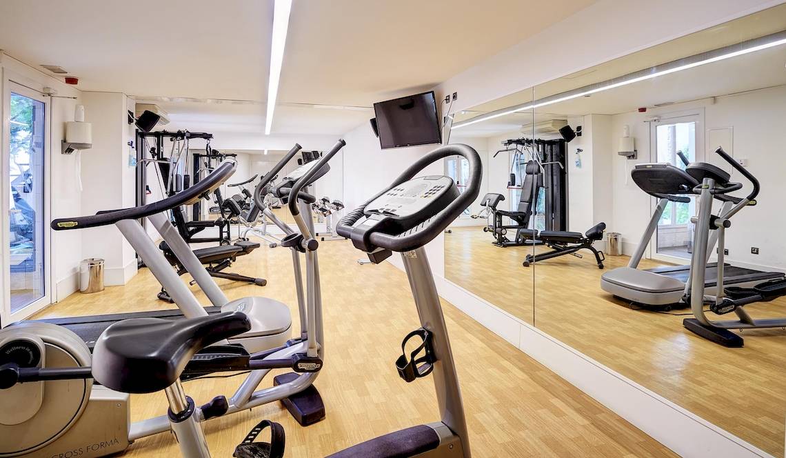 Fitnessraum im Hipotels Hipocampo Playa mit diversen Trainingsgeräten und einem großen Spiegel.