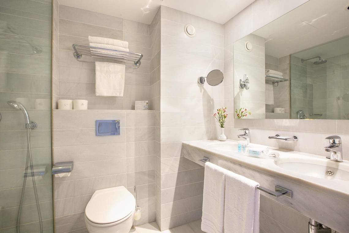 Badezimmer des Hipotels Hipocampo Playa mit weißen Fliesen und modernen Armaturen.