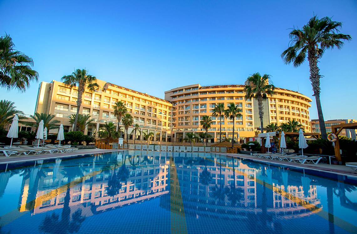 Außenansicht des Fame Residence Lara & Spa Hotels mit großem Swimmingpool und Sonnenliegen