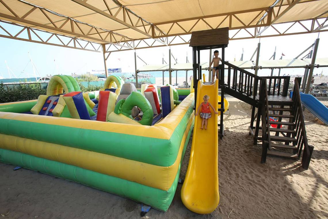 Zwei Kinder spielen auf einem großen, bunten aufblasbaren Spielplatz am Strand.