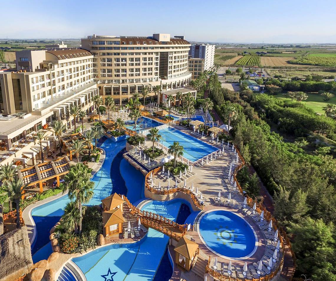 Luftaufnahme des Fame Residence Lara & Spa Hotels mit mehreren Swimmingpools und Sonnenliegen