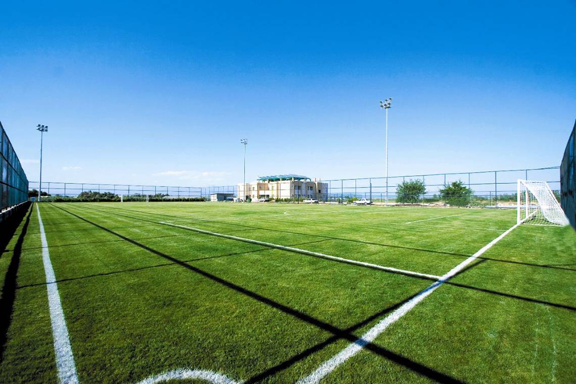 Ein leerer Fußballplatz im Freien mit weißen Linien und Gebäuden im Hintergrund beim Fame Residence Lara & Spa.