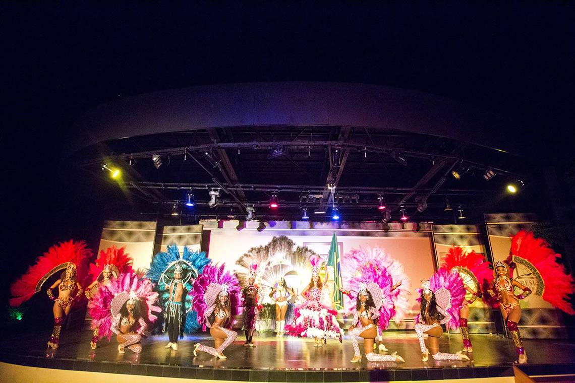 Brasilianische Tänzer in farbenfrohen Kostümen präsentieren eine Show auf einer Bühne bei Nacht.