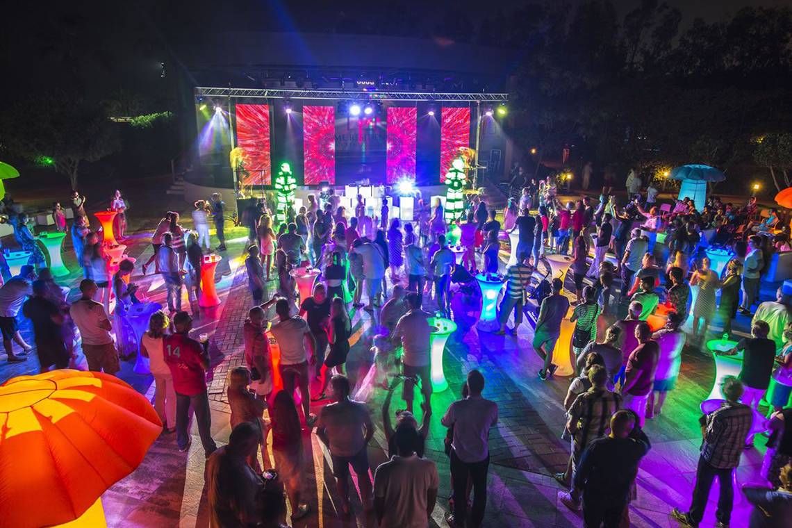 Nachtveranstaltung im Fame Residence Lara & Spa mit bunten Lichtern und vielen Gästen.
