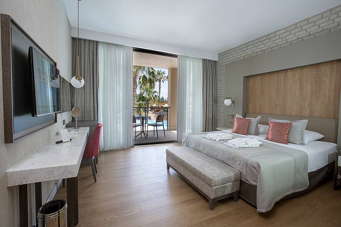 Hotelzimmer im Fame Residence Lara & Spa mit Balkon, Bett, Schreibtisch und Fernseher.