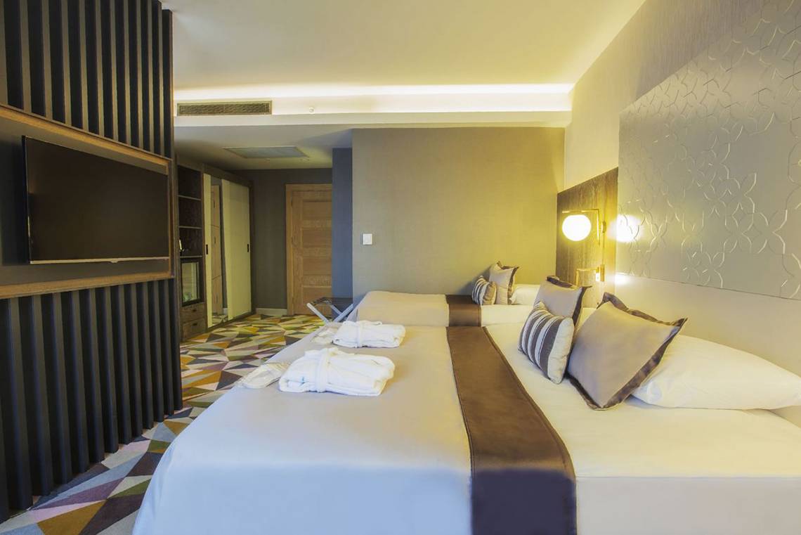 Doppelzimmer mit zwei Betten im Fame Residence Lara & Spa Hotel, geräumig mit modernen Möbeln, Fernseher, bequeme Betten und ein Teppichboden.