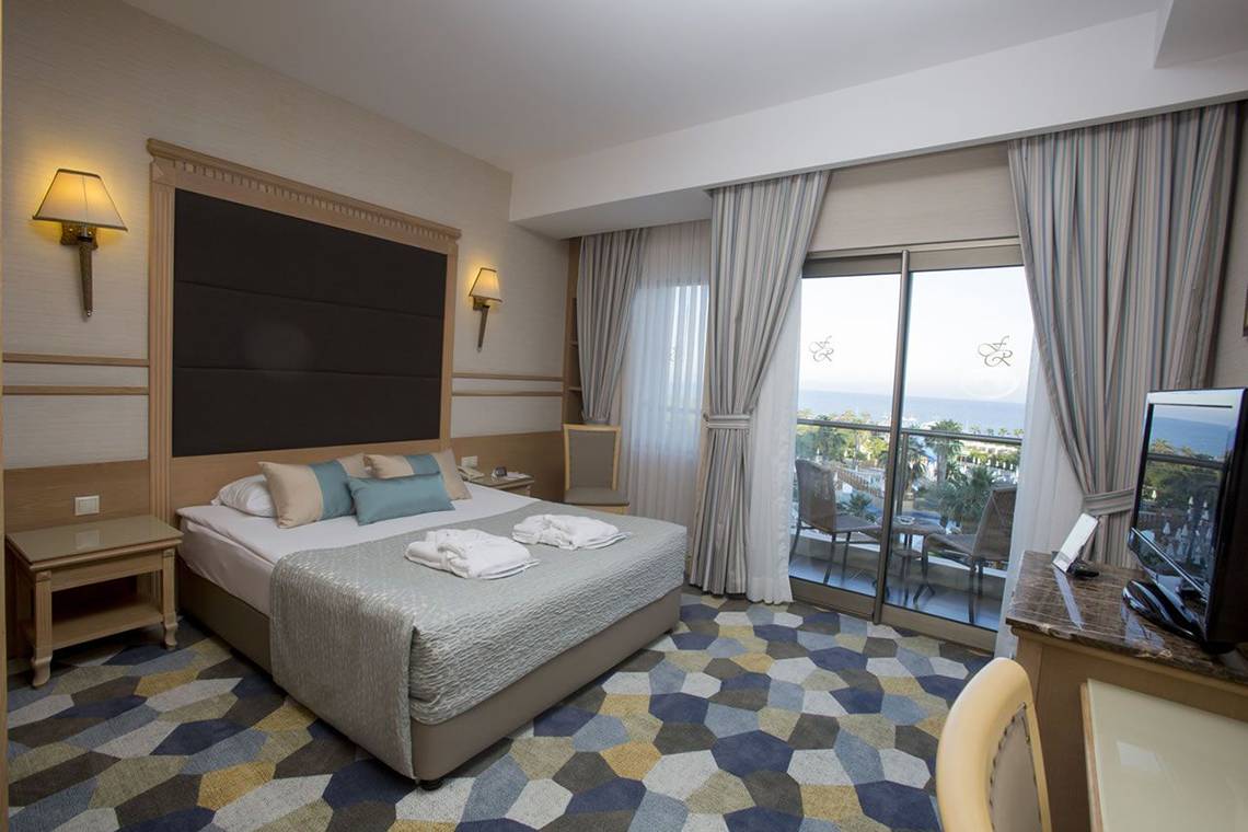 Hotelzimmer mit Meerblick im Fame Residence Lara & Spa mit einem Bett, zwei Nachttischen, einem Fernseher, einem Balkon und Blick auf den Ozean.
