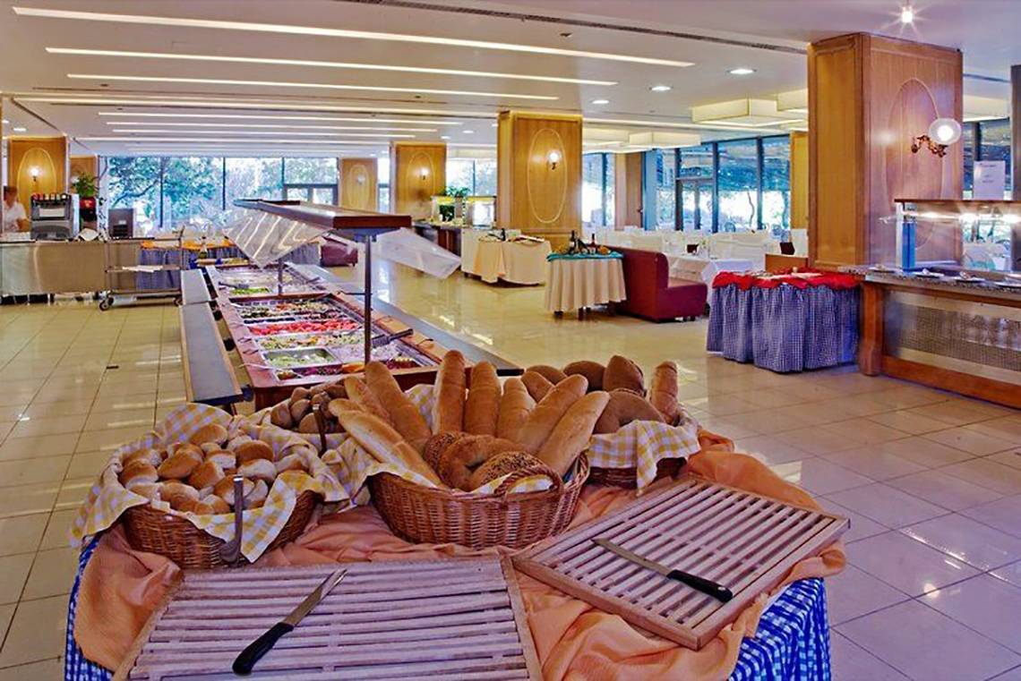 Buffet-Tisch im Caravia Beach Hotel mit verschiedenen Brotsorten und Schnittbrettern.