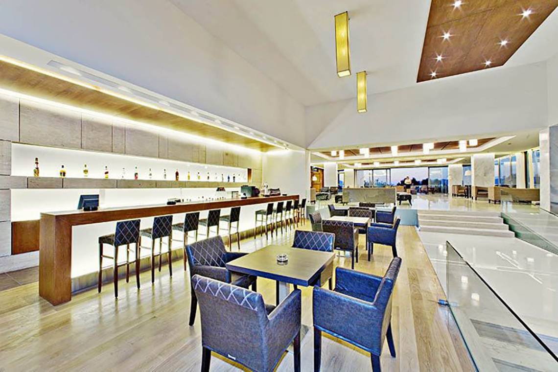 Innenansicht der Bar im Caravia Beach Hotel & Bungalows mit Holzboden, Bar-Theke, Tischen und Stühlen.