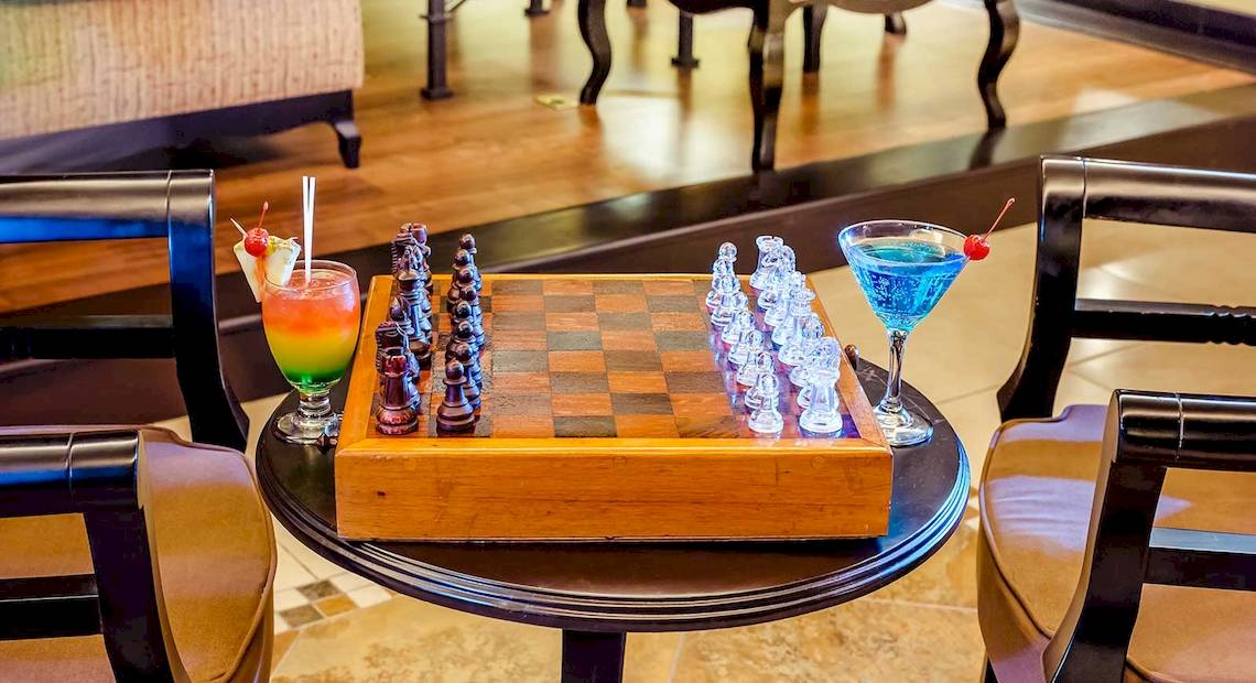 Ein holzner Tisch mit einem Schachbrett und zwei Cocktails auf dem Occidental Papagayo Hotel.