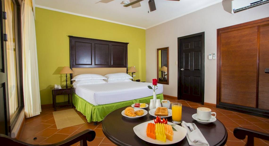 Hotelzimmer im Occidental Papagayo mit Frühstückstablett, Bett, Klimaanlage und Türen.