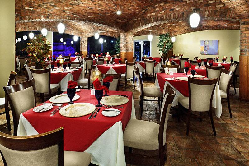 Restaurant-Innenbereich des Holiday Inn Resort Aruba mit roten Tischdecken und gedeckten Tischen.