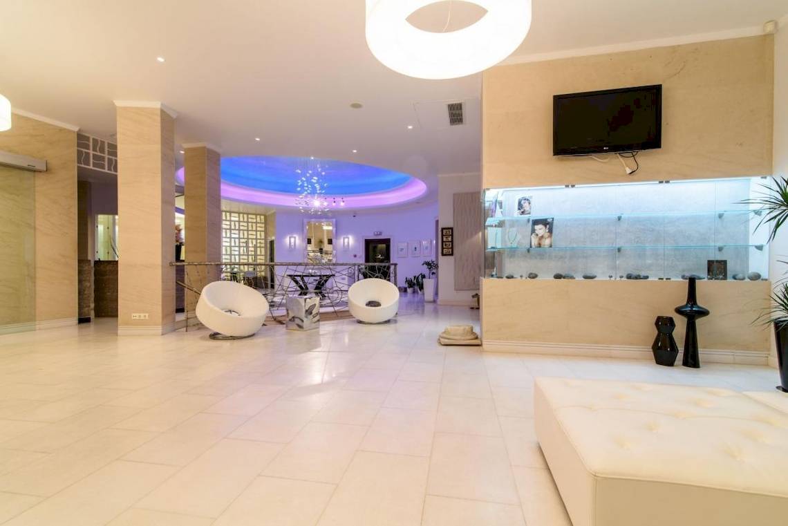 Lobby des La Mer Deluxe Hotel & Spa mit weißen Möbeln, einer Fernsehwand und blauer Beleuchtung.